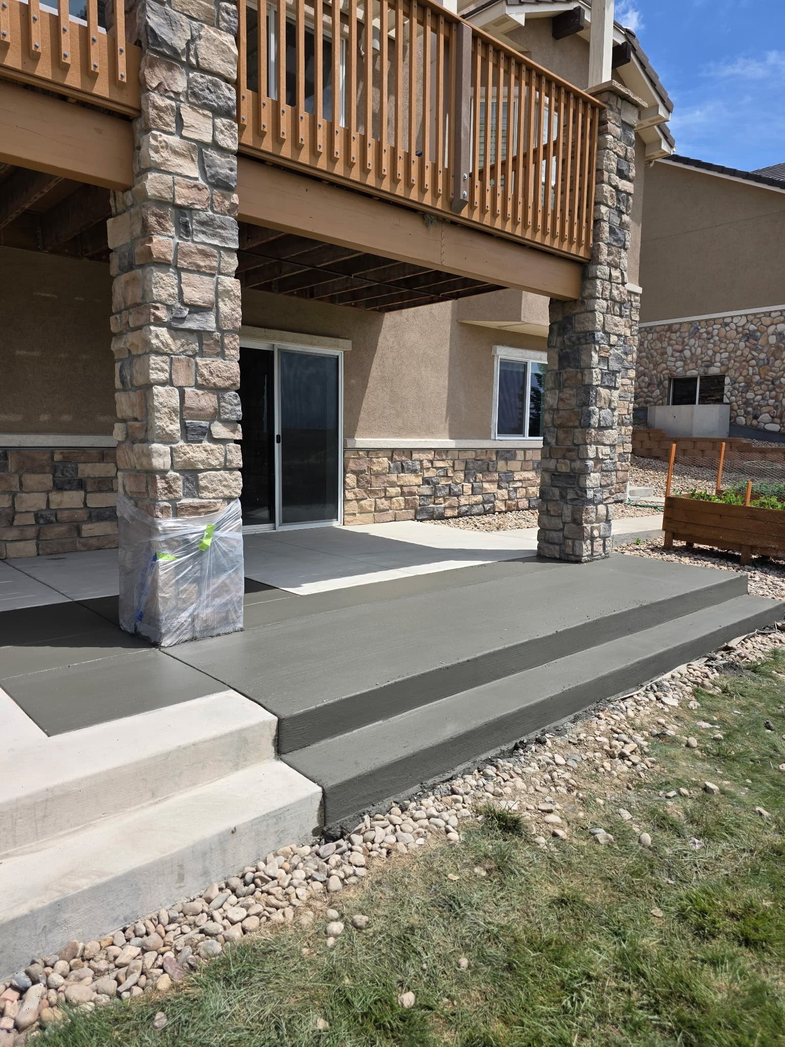 Covered concrete patio and steps framed by stone columns