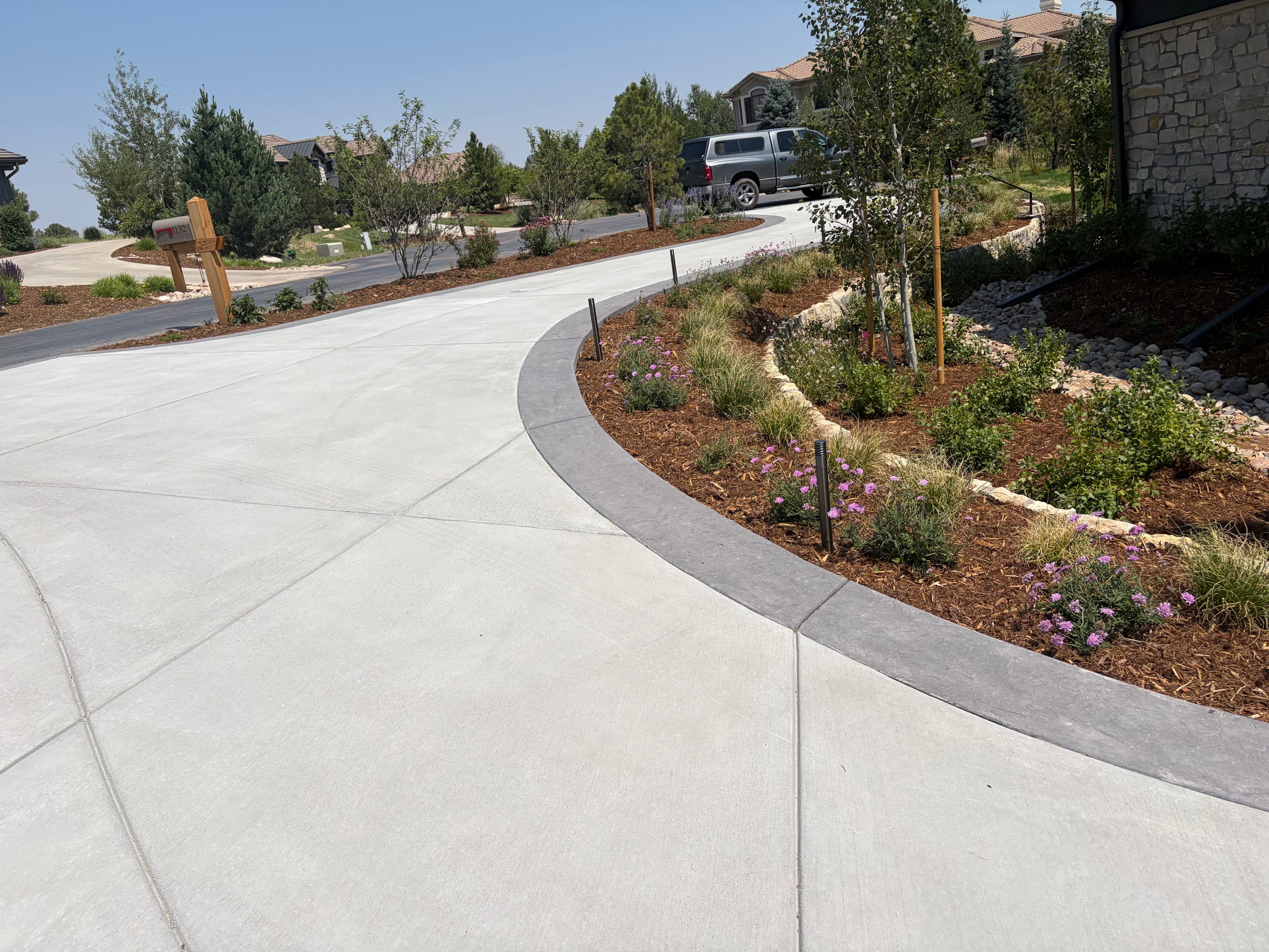 Newly poured concrete driveway curving past landscaped beds at a Denver-area home